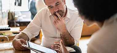 Ein Mann betrachtet eine Speisekarte und scheint nachzudenken.