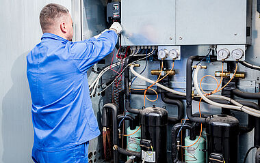 Techniker wartet eine industrielle Kühlanlage mit verschiedenen Anschlüssen.