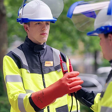 Techniker überprüfen mit Messgerät elektrische Anlagen im Freien.