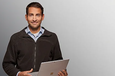 Ein Mann hält einen Laptop in der Hand.