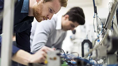 Techniker inspiziert und justiert elektronische Komponenten in einer Werkstatt.