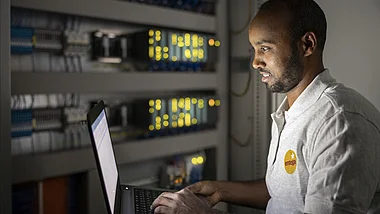 Techniker arbeitet in einem Serverraum an einem Computer.