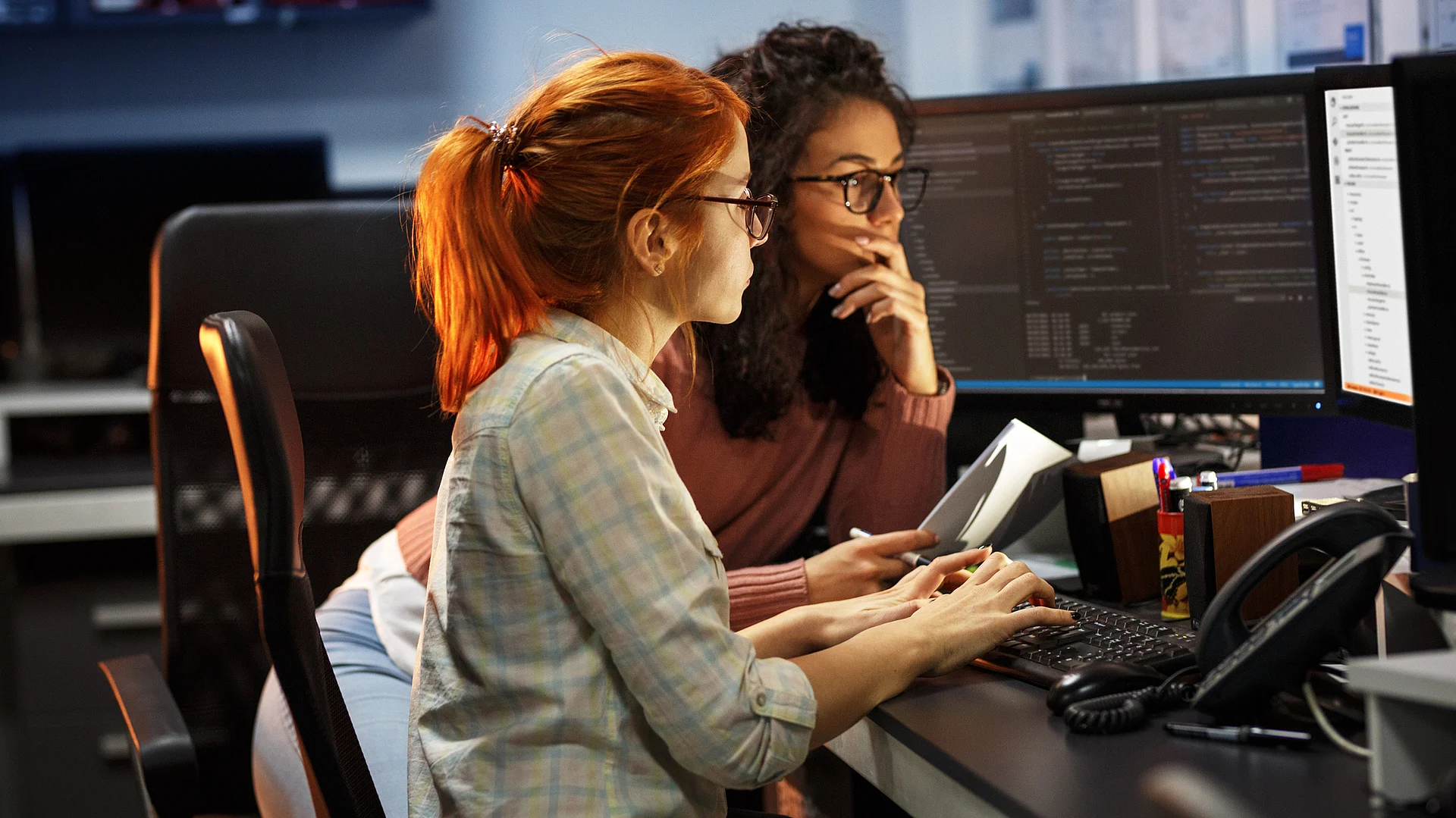 Zwei Ingenieurinnen arbeiten konzentriert an Computern in einem modernen Büro.